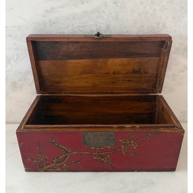 Vintage Chinese red storage box with hand painted Asian design of gilt vines and ring handle to open.