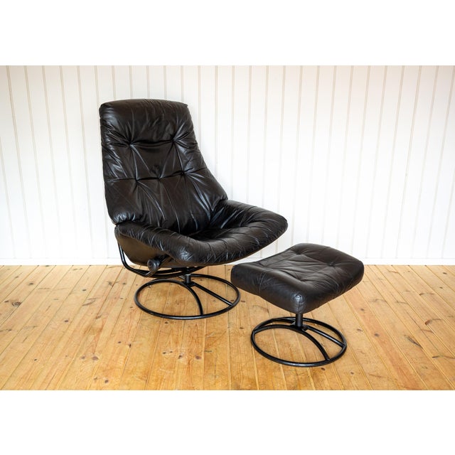 An ultra-comfy, rare and strikingly attractive Scandinavian black leather lounge chair and footstool in lovely vintage...