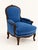 A beautifully shaped armchair featuring a carved wood frame, curved arms, and richly textured blue chenille upholstery....