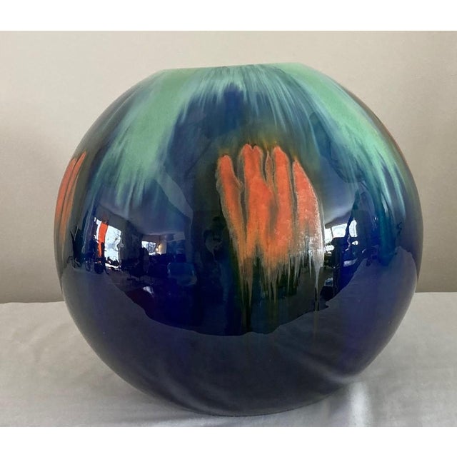 This beautiful vase is decorated like the northern lights in blues, greens, oranges. Shaped like a large globe, makes a...
