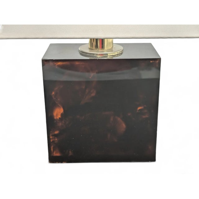 This elegant table lamp combines modern design and quality materials. The base is made of glossy resin with a...