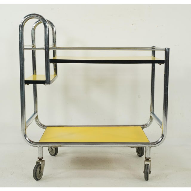 European Mid Century style bar or serving cart made of a chrome finished steel frame and two yellow and black trim Formica...