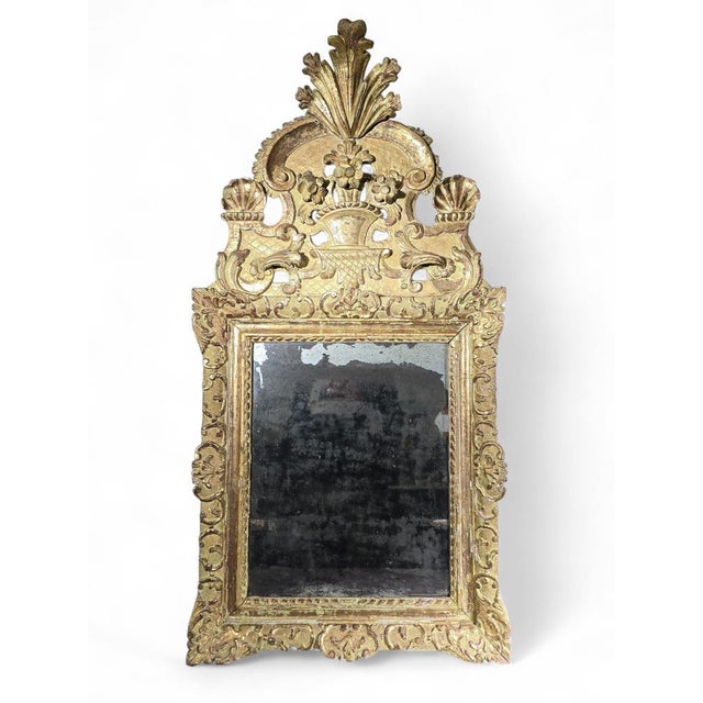 Elegant 18th-century French mirror with a carved wood frame, partially gilded, showcasing refined Rococo or Louis XV-style...