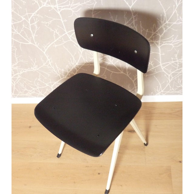 The "Result" chair, designed by Friso Kramer, is shown here with a matte black seat and backrest and a cream steel frame....