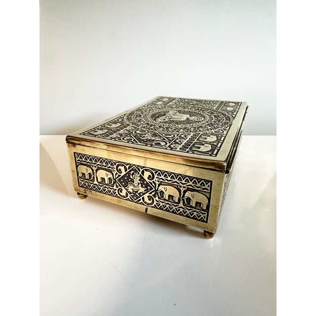 A decorative brass box with a cedarwood core, featuring Art Deco ornamentation with Asian motifs such as elephants,...