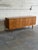 This minimalist lowboy features a wide rectangular frame with a symmetrical configuration of nine stacked storage drawers...