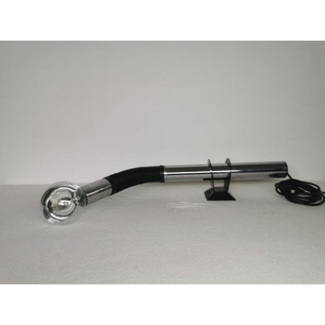 An italian design gooseneck wall lamp, made of a ribbed black plastic tube and chromed metal. The table lamp version...