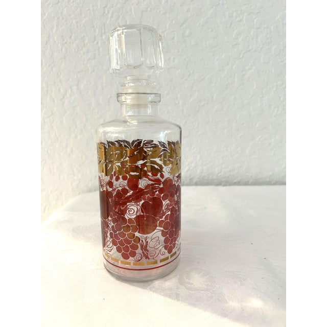 Pretty vintage French clear glass decanter and six footed cordial glasses featuring a fruit vine-motif in a deep shade of...