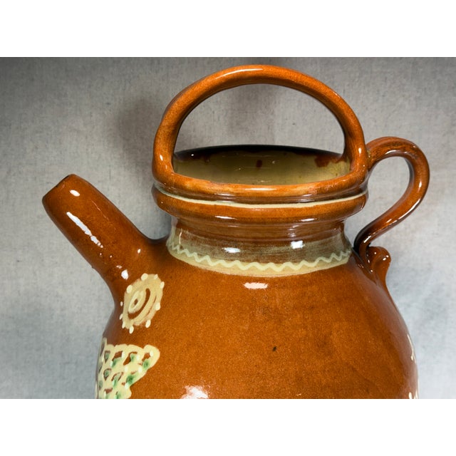 This artisan-made, hand-thrown and hand-glazed French terracotta jug features an inscription that translates approximately...