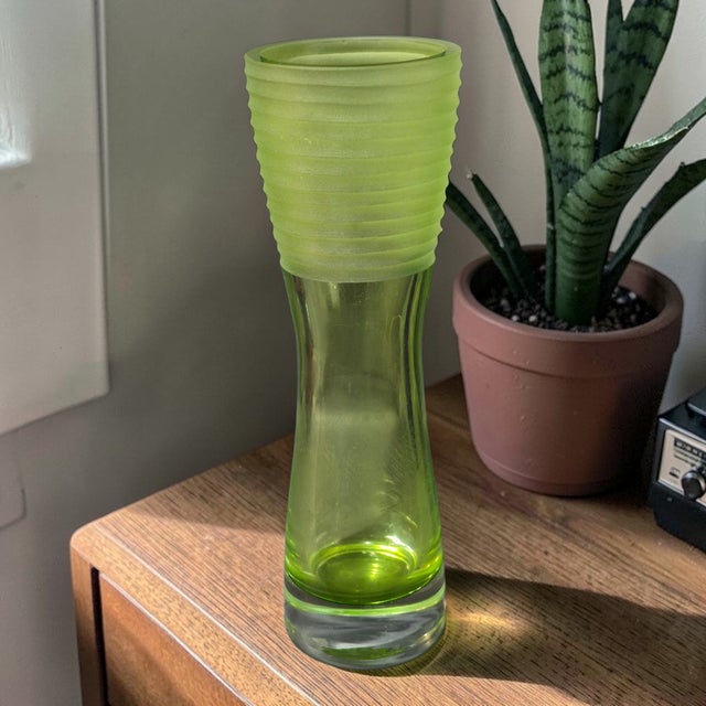 This vintage Mid-Century Modern art glass vase features a vibrant green color with a textured and ribbed design, adding a...