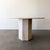 Sculptural vintage round dining table crafted entirely from solid travertine stone, featuring a substantial hexagonal...
