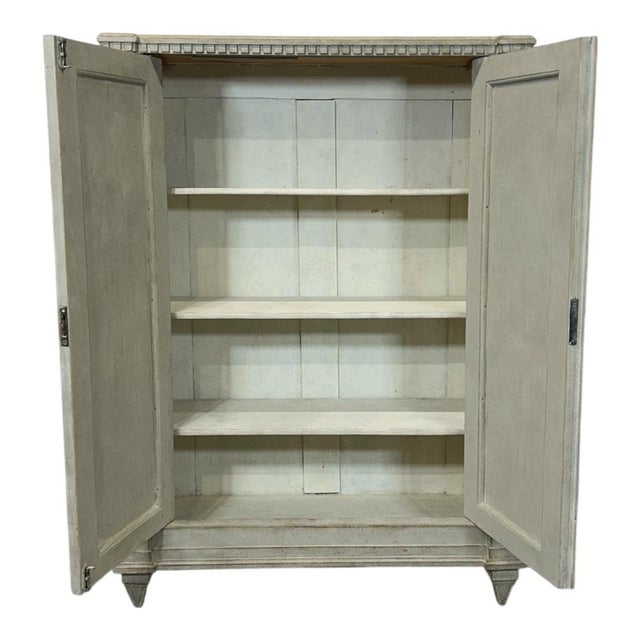 A simple and elegant light grey Swedish antique buffet. A decorative strip with serrated edges sits beneath the top. Two...