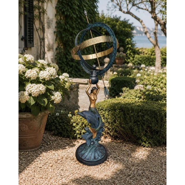 A beautifully crafted armillary sphere featuring a mermaid and dolphin, evoking the timeless elegance of coastal or Palm...