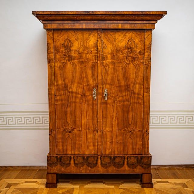 Two-door wardrobe with a straight carcass. The carcass is veneered in walnut. The doors display a mirrored veneer pattern....