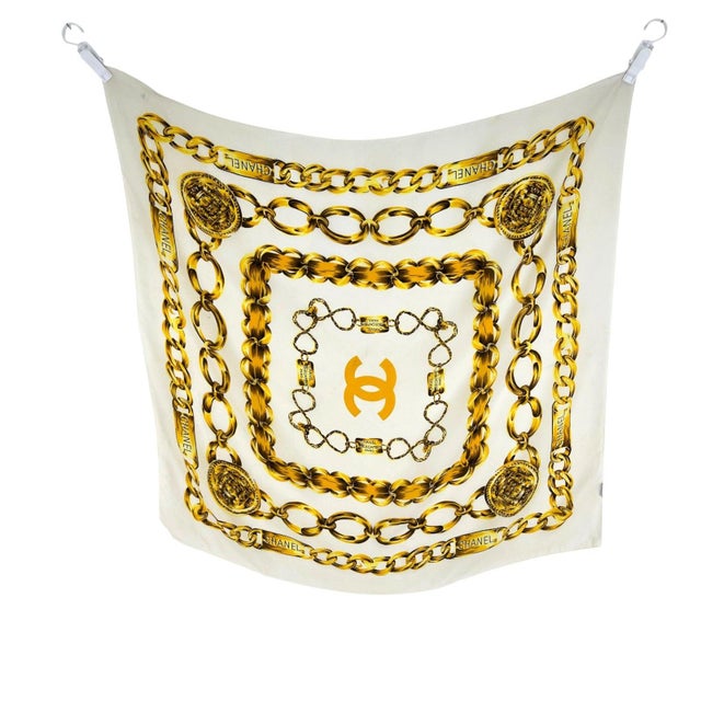 Chanel White Printed 100% Silk Scarf. Off-white ground with gold chain-link borders, CHANEL plaques and coin medallions,...