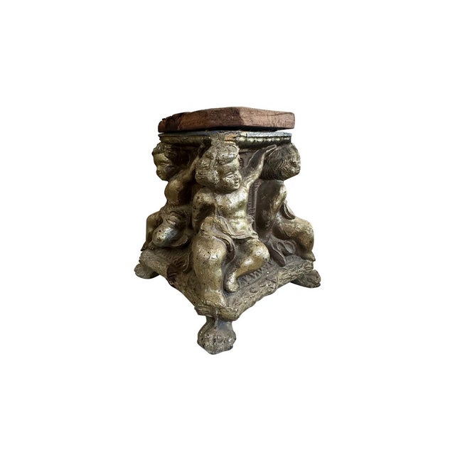 This tin cast sculpture has a paw footed base and a wooden top. Putti figures are at each corner of the cast. It would be...
