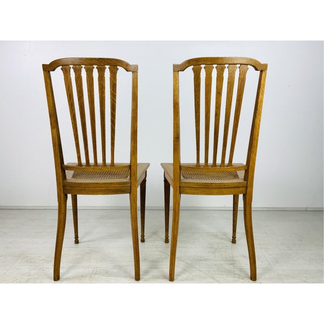 A pair of Louis XVI style side chairs in a slight golden oak finish with tall back with an arched crest rails, five...