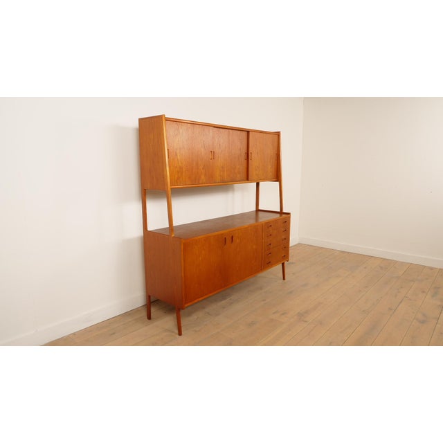 A beautiful and unique vintage open cabinet, crafted from warm teak. A piece of furniture with a striking and highly...