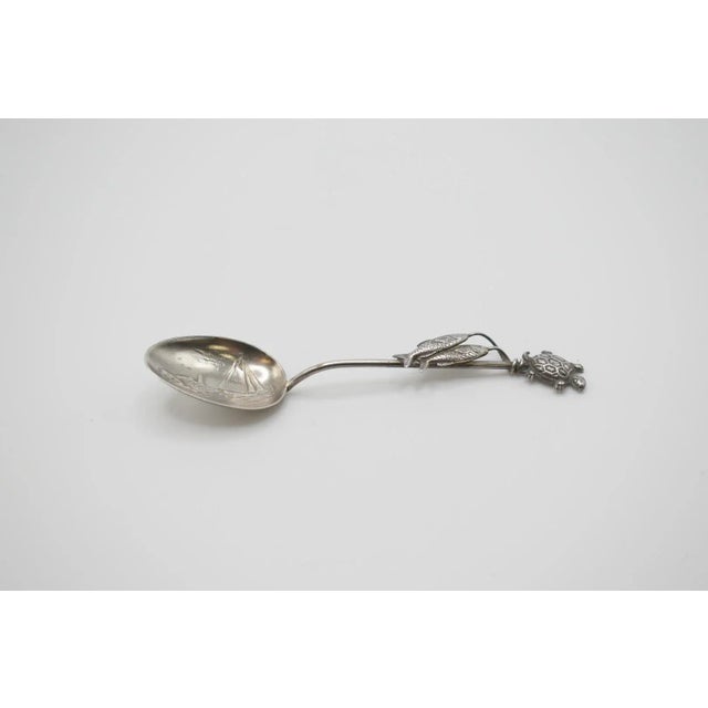 This is a darling silver spoon with a nautical theme. There is an engraving of a sailboat and lighthouse scene on the bowl...