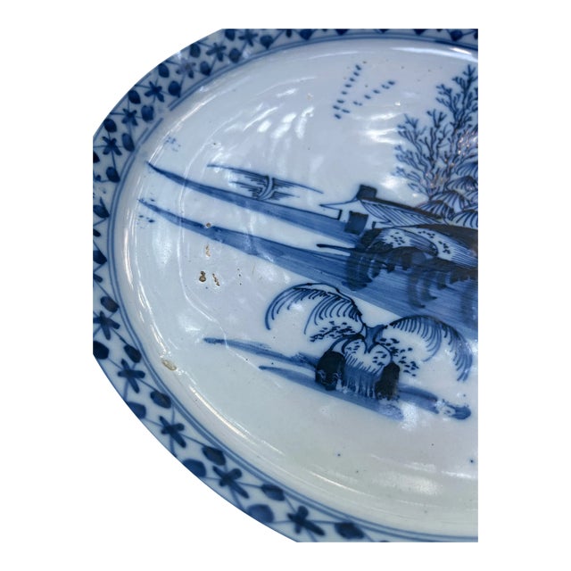 A single large antique porcelain bowl. Possibly Dutch or English with Chinese style blue and white glaze landscape...