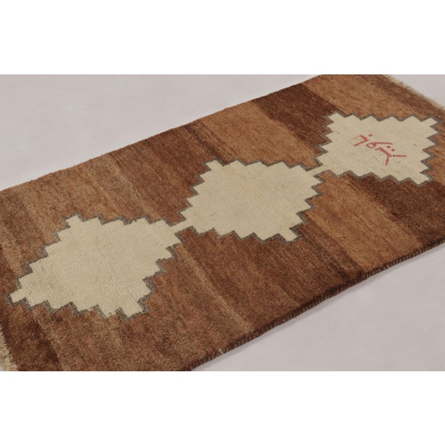 Hand-knotted in wool circa 1950-1960, this 3x6 vintage Persian Gabbeh runner rug is a captivating example of nomadic...