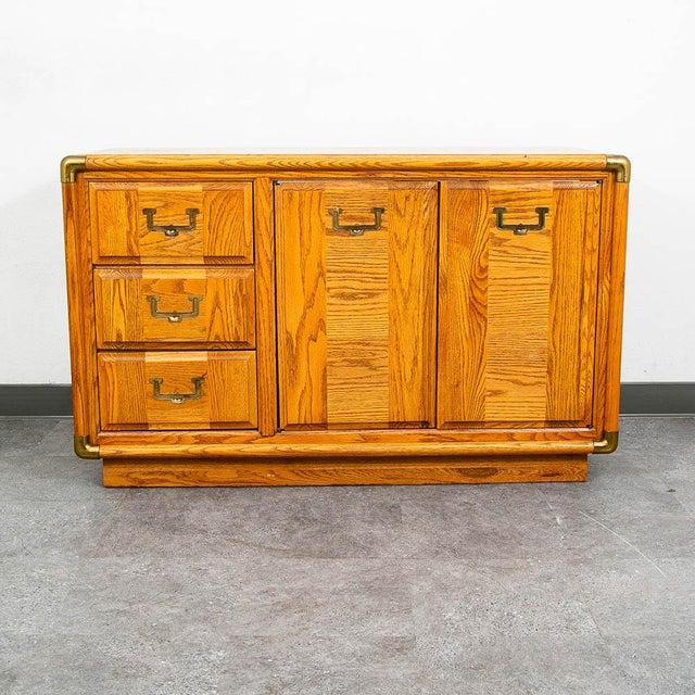American designed oak dresser with a unique solid oak wood and brass design. This piece has 3 drawers within and 2 cabinet...