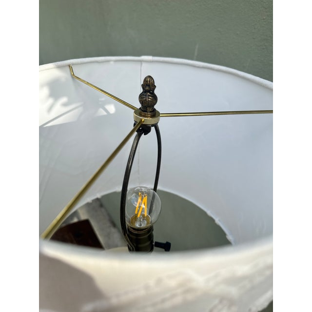 A refined vintage table lamp with a white ceramic draped-shell base in lustrous ivory glaze. Fitted with a custom white...