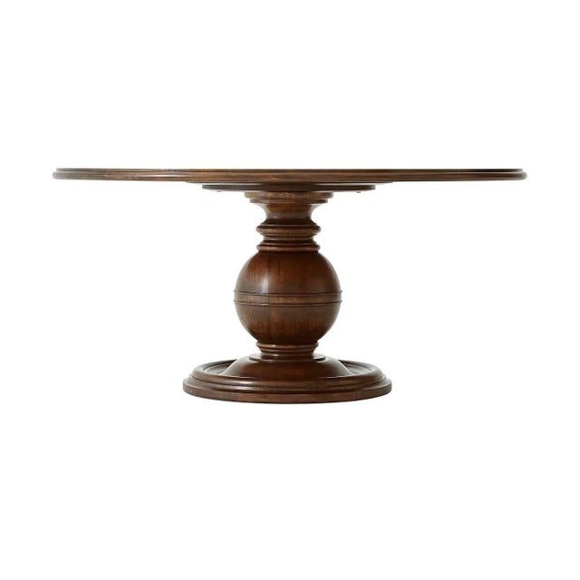 A French Art Deco mahogany and cerejeira dining table, the circular crossbanded and molded edge top above a sphere and...