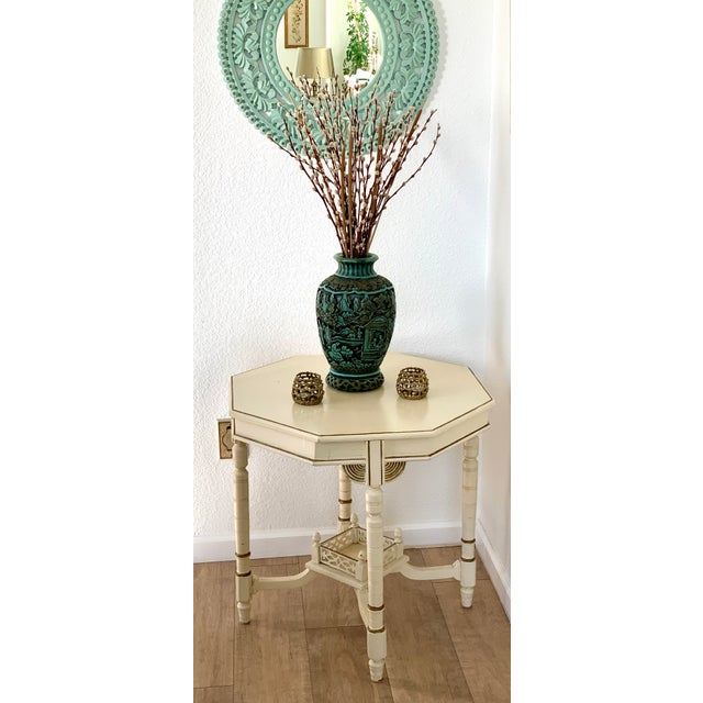 Asian chinoiserie mid-century, elegant accent table. Cream colored with gold accents, and lots of carved detailing on the...