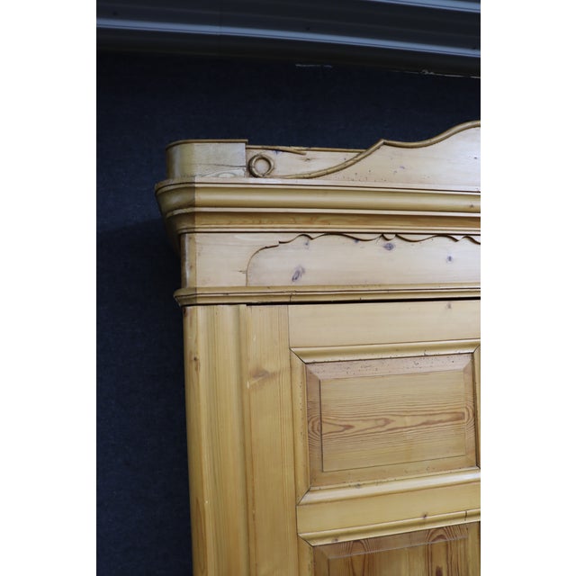 Solid pine armoire featuring paneled double doors and a warm, natural finish that highlights the wood grain and character....