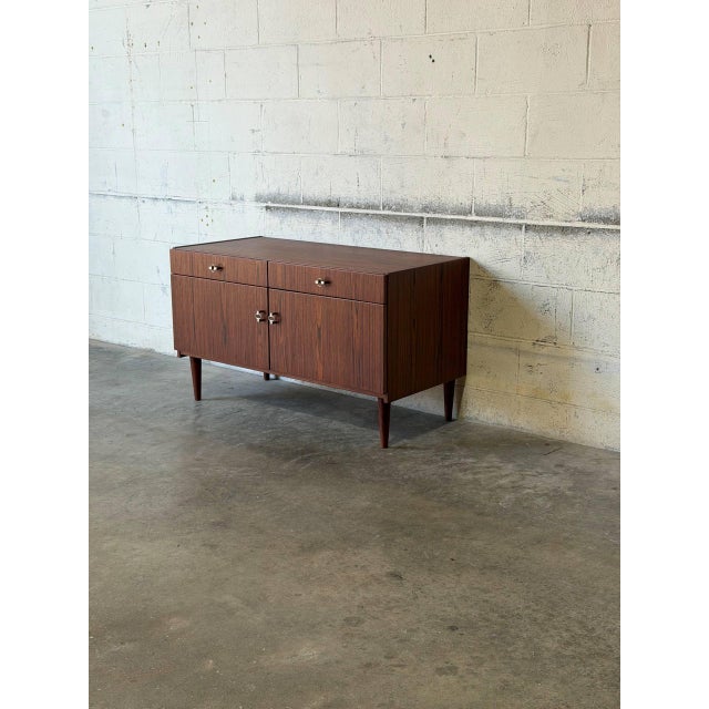 This storage piece features a clean silhouette elevated by tapered legs. The front is defined by a balanced arrangement of...
