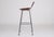 A bar stool with a slightly raised back, often attributed to charlotte perriand. Cognac leather seat riveted to a chromed...