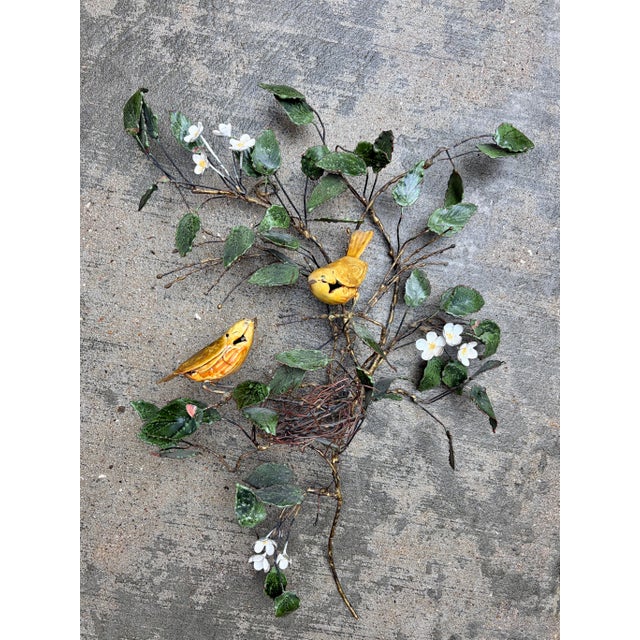 A charming vintage handcrafted metal wall sculpture depicting two golden songbirds perched among flowering branches and...