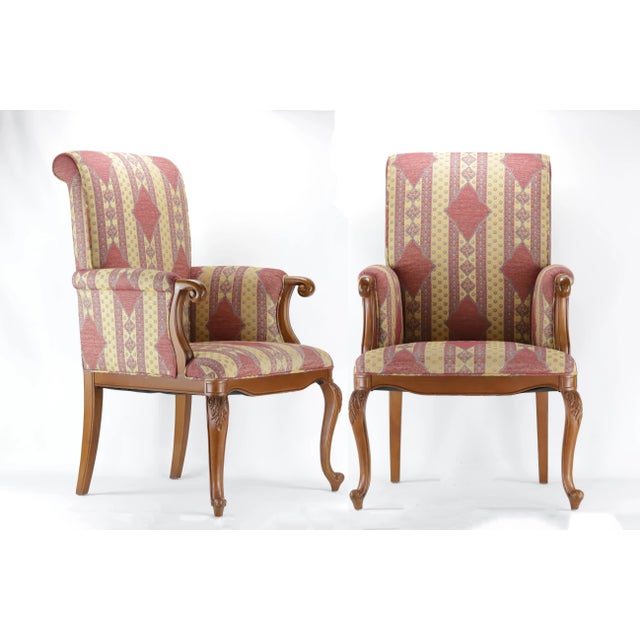 A fine pair of vintage wooden armchairs with upright padded back, armrests, and floppy cushioned seats upholstered in...