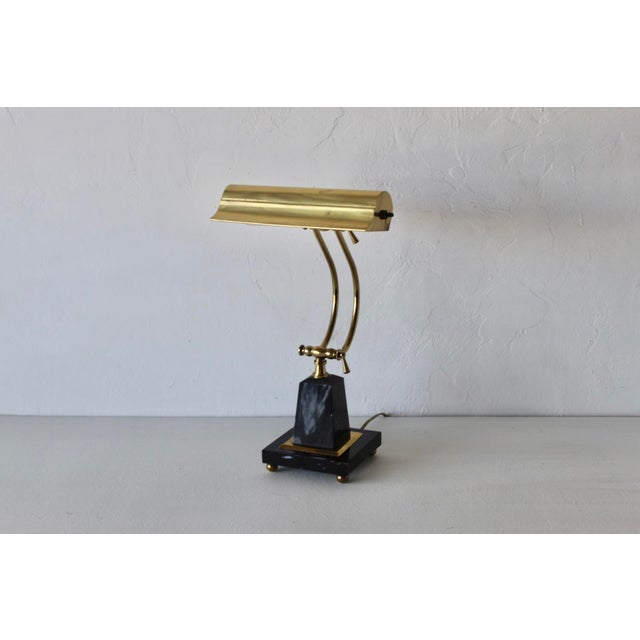 Vintage classic-style polished brass and black marble piano/bankers desk lamp. Polished brass hood and dual curved neck,...