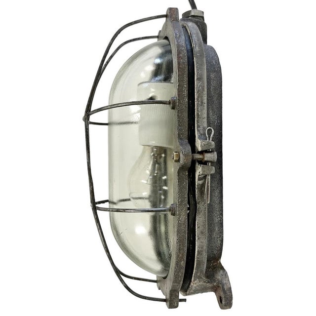 Industrial wall light made in Poland during the 1960s. It features a cast iron body, a clear glass cover and a steel grid....