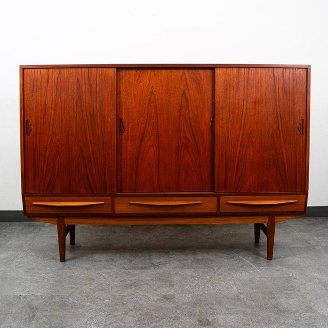 Handsome Rich sculptural Scandinavian Danish modern teak wood Credenza / Highboard. Comes with 3 doors that slide open and...