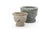 A collected set of three stone mortars, each turned with a thick rolled rim and a footed base. Two are in a speckled sand...