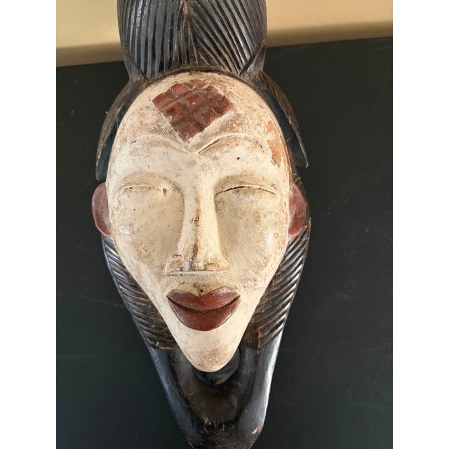 This is a vintage African Punu mask from Gabon. It is made of wood. It was made in the 20th century It is white and brown...