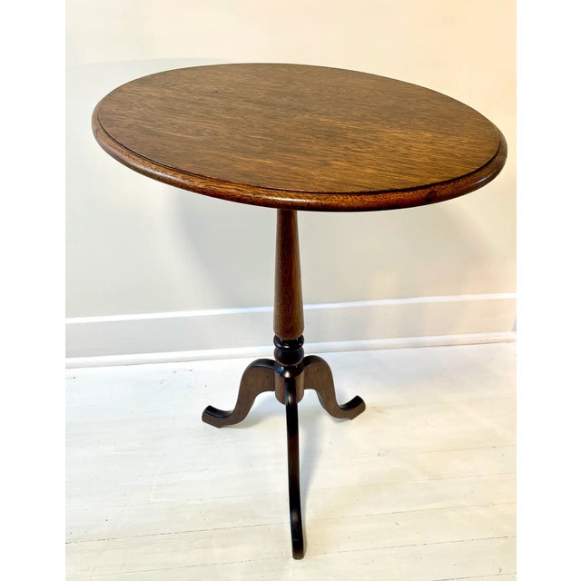 Oak tilt top table with turned pedestal and exaggerated, arched legs. Beveled edge on top. Tilt top with metal latch....