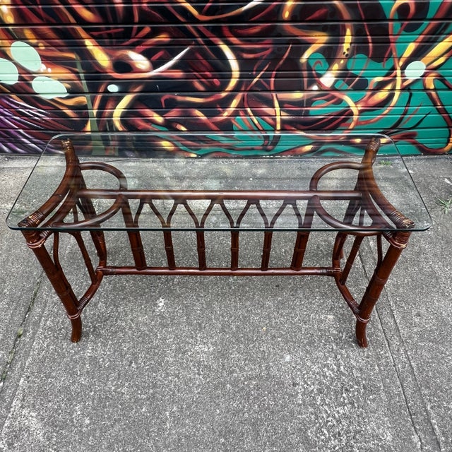 1970s bamboo rattan console table with 1/2” thick glass. The bamboo frame features sculptural curved detailing and woven...