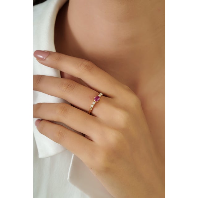 This elegant five stone ring features a 0.34 carat oval ruby set 14K Yellow Gold. The ruby measuring 4 x 5 mm, beautifully...