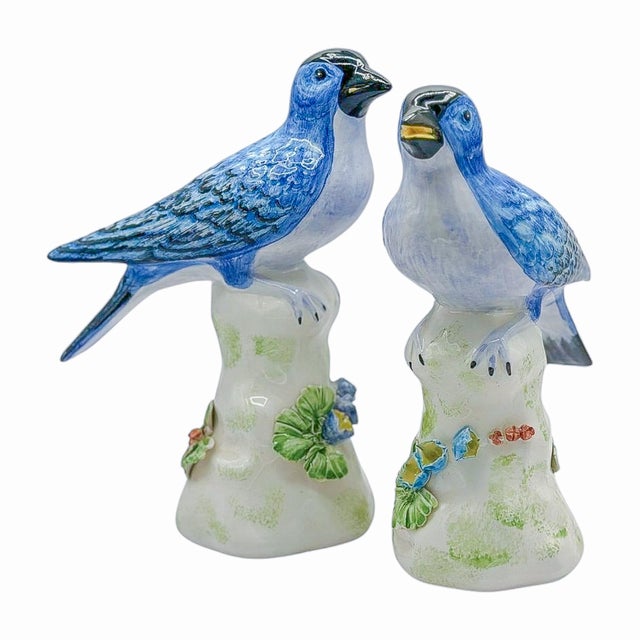 A pair of vintage Chelsea House bird figures with blue-and-white plumage, long tails, and pale leafy bases accented with...