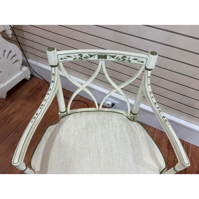 A charming pair of neoclassical armchairs in the Directoire / late Sheraton taste. Each chair features a cream-painted...