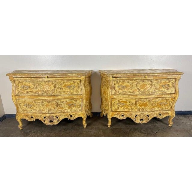 A wonderfully decorative pair of Louis XV–style bombe commodes, richly carved and finished in an exceptional timeworn...