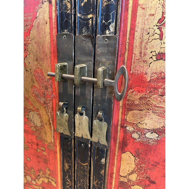 This beautiful two doors cabinet is made of black and red lacquered wood presenting Chinese sceens and decorations in gold...