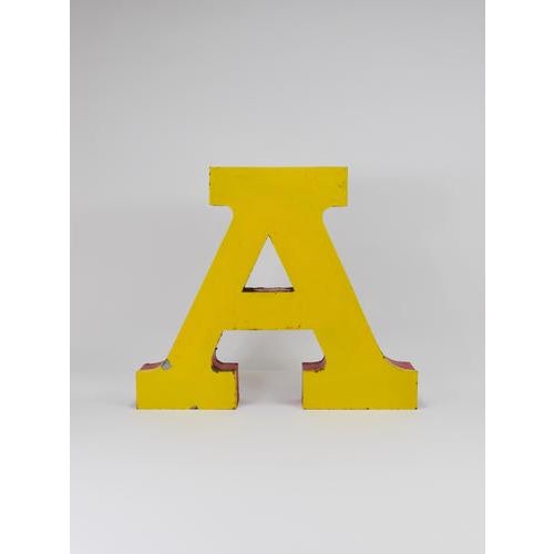 A beautiful and decorative large vintage tin channel letter “A” made of sheet metal, painted in a vibrant yellow with red...