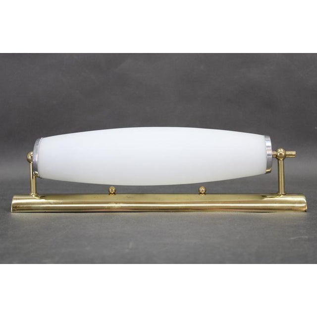 A refined art deco wall light crafted in italy in the 1940s, showcasing a harmonious blend of polished brass and a softly...