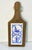 A pretty wood and tile trivet that has a leather strap to hang when not in use. It features a large hand-painted ceramic...