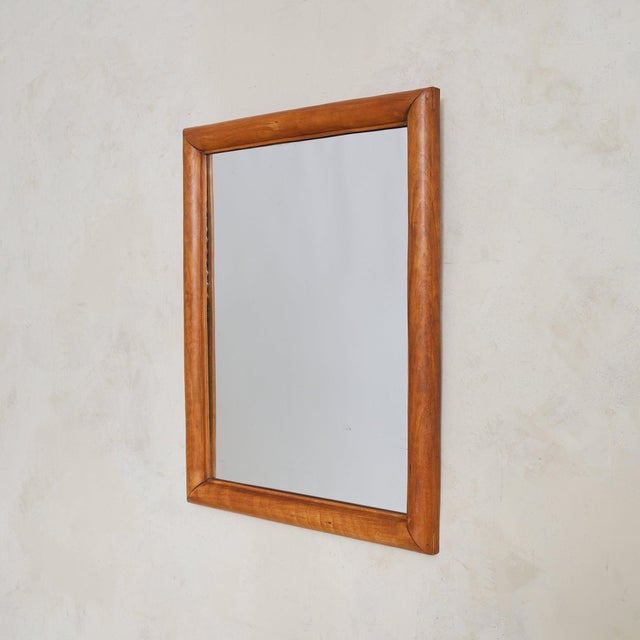 A 1950s Italian wall mirror with a soft, architectural presence. Framed in solid wood, its rectangular form features...